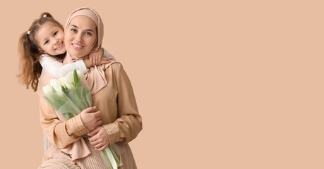 Muslim woman with tulips and her little daughter on beige background with space for text. Mother's Day celebration