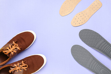 Pair of stylish shoes with orthopedic insoles on lilac background