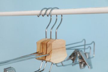 Rack with metal clothes hangers on blue background