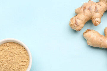 Fresh ginger roots and bowl with dried powder on blue background