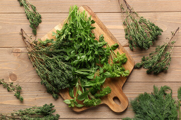 Cutting board with different fresh herbs on wooden background © Pixel-Shot