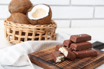 Wooden board with tasty chocolate covered coconut candies on table
