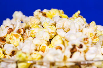 Bowl full of healthy butter popcorn on blue background