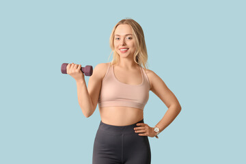 Beautiful young sporty woman with dumbbell on blue background. Weight loss concept