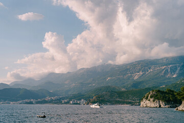 Motor yacht sails on the sea along the mountain coast