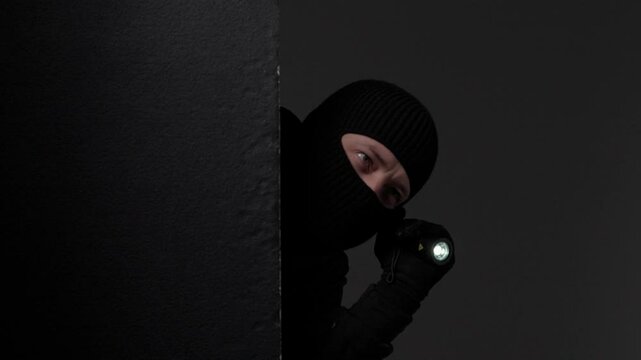 Masked Intruder Holding Flashlight in Darkness
