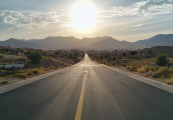 Naklejka premium Serene Road Leading Towards Majestic Mountains Under a Bright Sky at Sunset in a Tranquil Desert Landscape