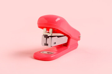 Red stapler on pink background