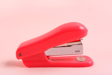 Red stapler on pink background