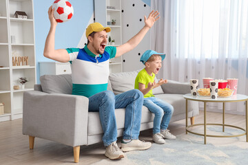 Fototapeta premium Young father and little son watching sports at home