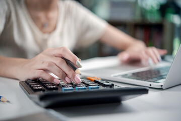 Businesswoman using a calculator and laptop for financial planning and budget management.Accountant...