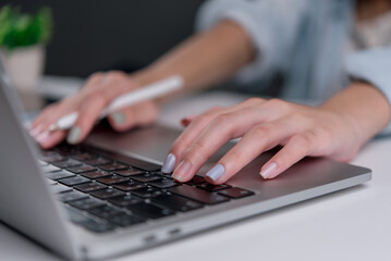 Close-up of a businesswoman typing on a laptop keyboard, representing remote work and digital productivity.