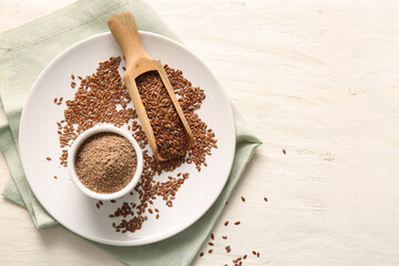 Wooden scoop with flax seeds and bowl of flour on white wooden background