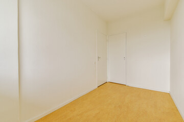A minimalistic view of an empty room showcasing plain white walls and a single closed door, with a warm colored floor. The space feels open and inviting.
