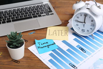 Sticky notes with text LATER, TIME MANAGEMENT, financial documents, alarm clock and laptop on...