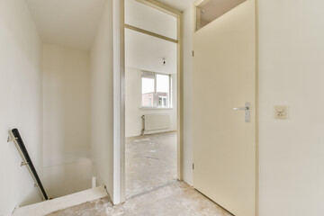 A minimalist interior space features an open door that leads to a staircase, showcasing bright white walls and a sense of openness.
