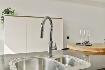 A contemporary kitchen sink featuring sleek design, chrome faucet, and an elegant countertop adorned with decorative elements, creating a modern cooking space.