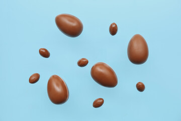 Delicious chocolate eggs flying on blue background