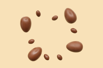 Frame made of chocolate eggs flying on beige background