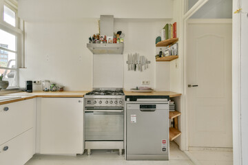 Fototapeta premium Bright and airy kitchen featuring sleek cabinetry, a modern stove, simple decor, and practical storage solutions. Ideal for contemporary living spaces.