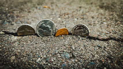 United States coins currency in a crack fault line of pavement. Concept of economy, loans, defaulting, recession or budget shortfall background.