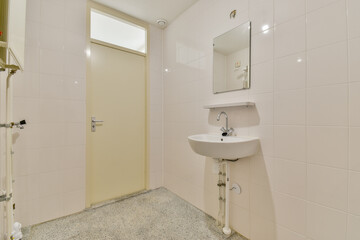 A sleek and tidy bathroom featuring white tiles, a simple mirror, and a compact sink design. Ideal for contemporary and minimalist aesthetics.