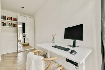 A sleek and modern home office featuring a minimalist desk, computer, and stylish bookshelf in a bright, airy room with warm wooden flooring.