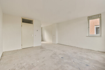 A spacious empty room featuring bare walls and a plain concrete floor, showcasing a minimalist aesthetic with natural light coming through the window.