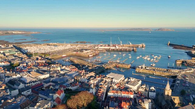 High drone flight from St Peter Port over the harbour and marinas with views out to Herm and Jethou in late afternoon sunshine