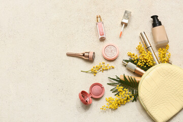 Cosmetic bag with different makeup products and mimosa flowers on white background