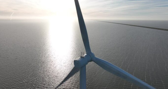 Offshore wind park, close up view of a large wind turbine on open water. Electricity generation.