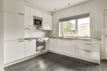 A sleek and stylish modern kitchen featuring white cabinetry, stainless steel appliances, and a clean layout, ideal for contemporary living spaces.