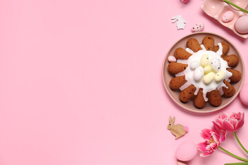 Plate of sweet Easter bread with eggs, rabbits and tulip flowers on pink background