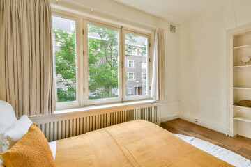 A warmly decorated interior showcasing large windows, soft textiles, and natural light, creating a serene and inviting atmosphere in a modern setting.