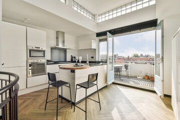 Bright and airy kitchen featuring sleek cabinetry, a stylish island, and an inviting balcony view perfect for relaxation and dining.