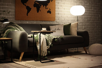 Modern interior of living room with comfortable sofa, coffee table and glowing lamps
