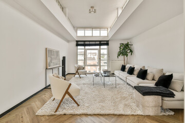 A spacious modern living room featuring a cozy white sofa, stylish decor, and large windows that flood the area with natural light.