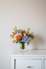 Colorful flower bouquet in glass jar on cabinet