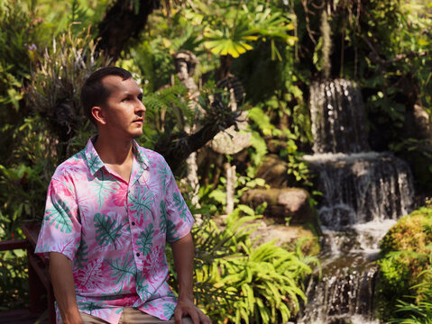 Man relaxing by a waterfall in a lush garden during daytime