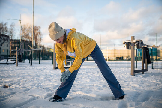 Woman stretching in snowy outdoor gym in winter
