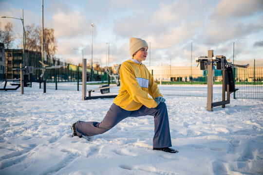 Woman stretching and performing a lunge outdoors in winter