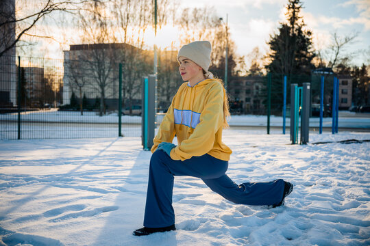 Woman stretching and performing a lunge outdoors in winter