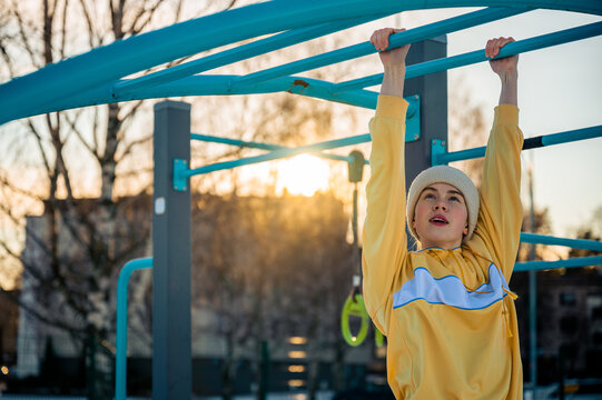 Young woman exercising on monkey bars in winter outdoor gym