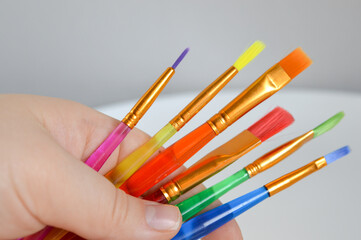 hand holding a set of colorful paintbrushes different shapes sizes art craft painting supplies...