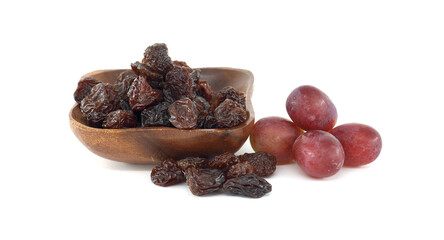 Wooden bowl brimming with dark raisins is presented alongside a cluster of red grapes