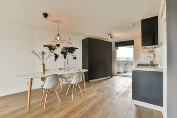 This interior showcases a sleek, modern kitchen with a dining area, featuring stylish furniture and a minimalist decor with wooden flooring.