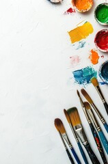 Fototapeta premium A white background with colorful paintbrushes and a palette, with space for text in the center of the design