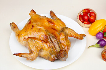 Generated imaA whole roasted chicken with crispy, golden-brown skin served on a white plate, accompanied by fresh vegetables like cherry tomatoes, bell peppers, and eggplants.ge