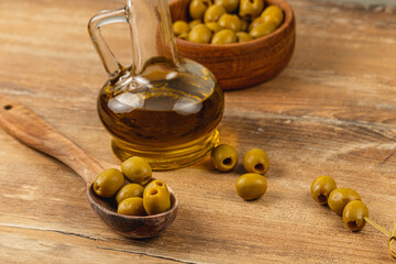 Olive oil and green olives on a wooden table create a rustic culinary display