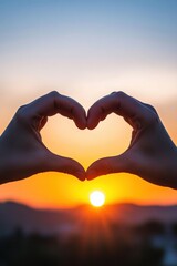 Silhouette of hands forming a heart shape against a vibrant sunset sky.